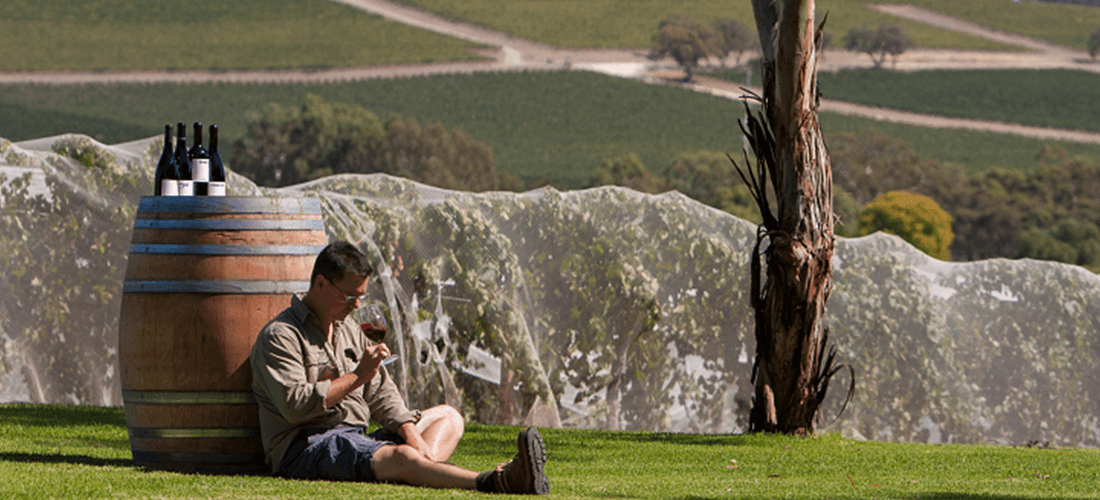 Tom White sitting in front of barrel drinking wine